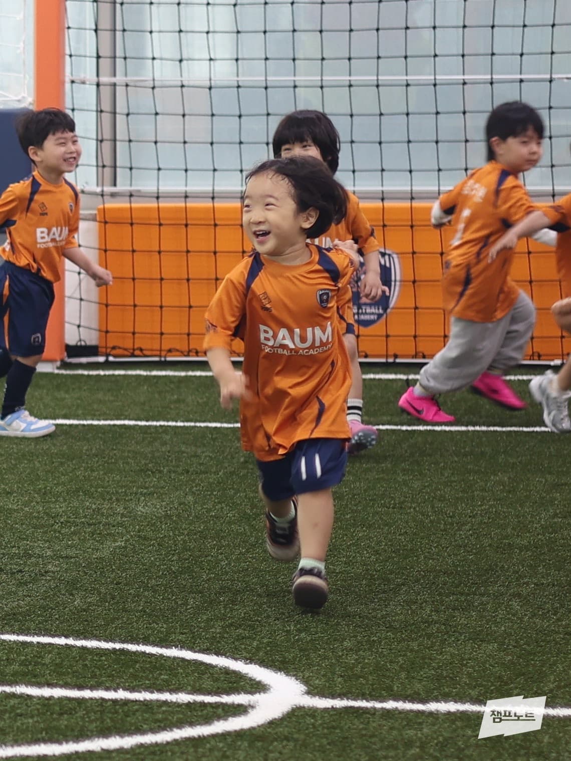 실내구장에서 웃으며 뛰는 아이